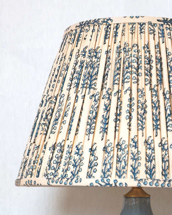 Blue ceramic lamp with a patterned beige and blue lampshade on a white background