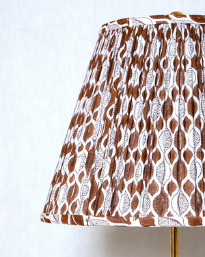 Lamp with a patterned brown and white shade on a plain background