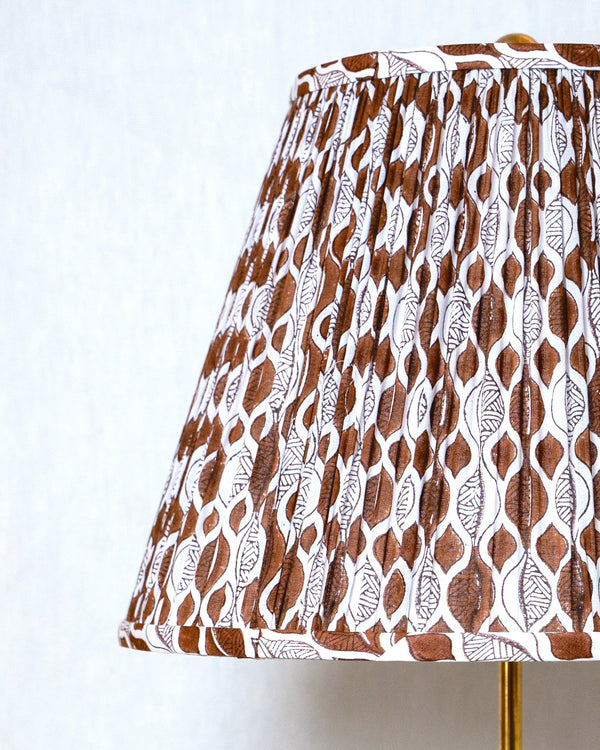Lamp with a patterned brown and white shade on a plain background