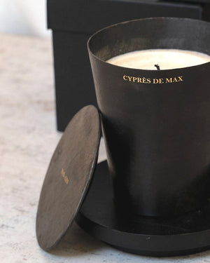 Black candle with lid and black packaging on a light surface