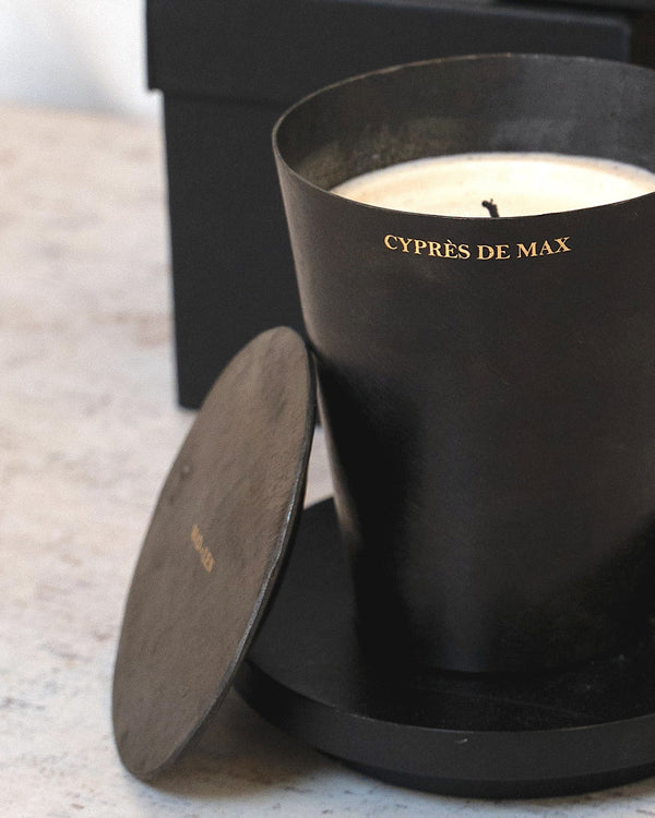 Black candle with lid and black packaging on a light surface